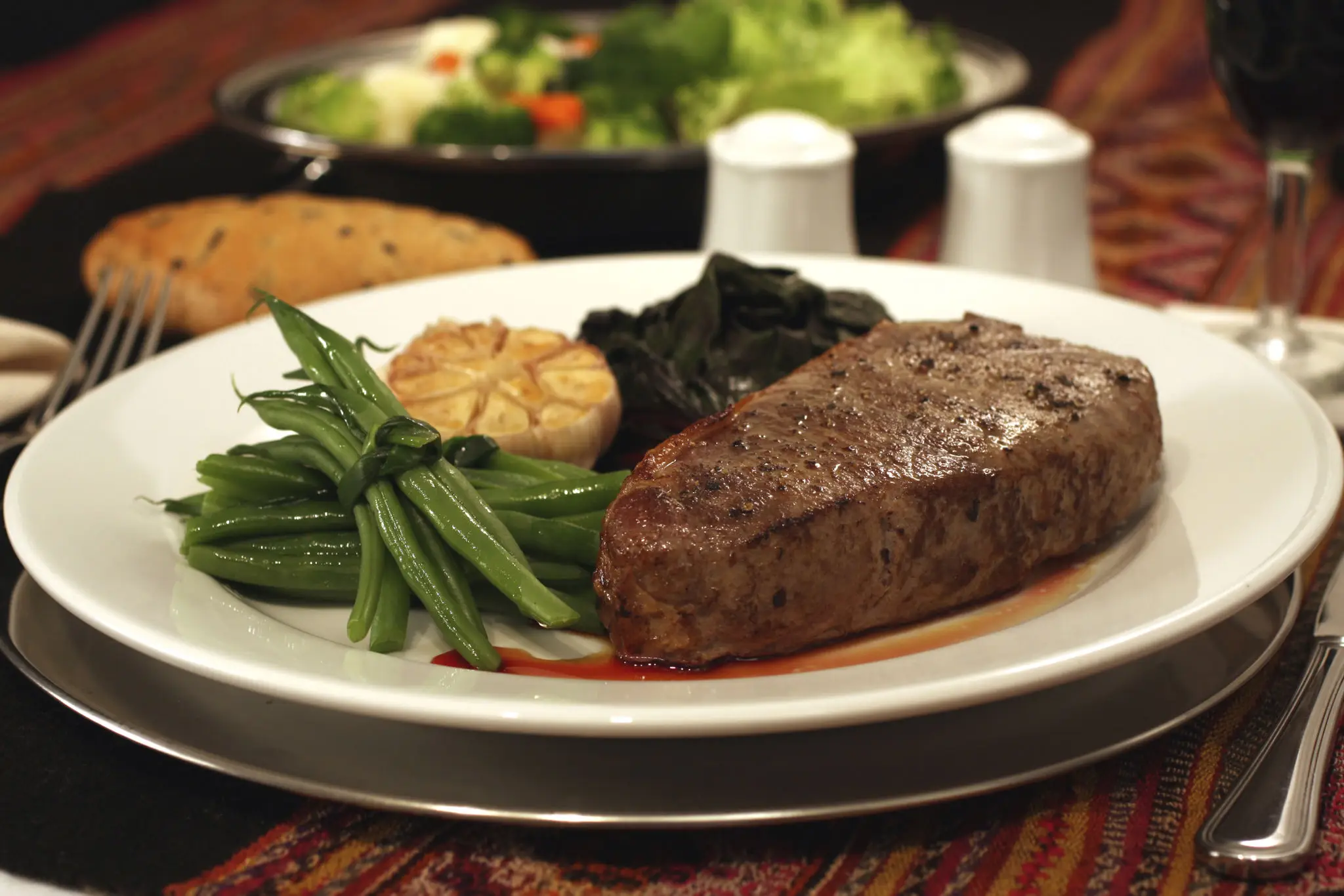 A plated steak dinner with green beans and mashed potatoes.