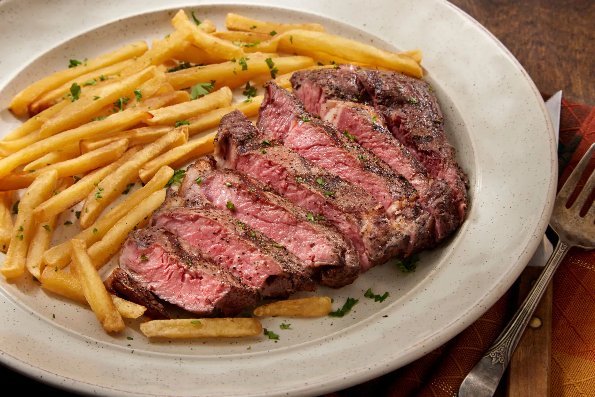 Sliced medium-rare steak with pasta on a white plate.